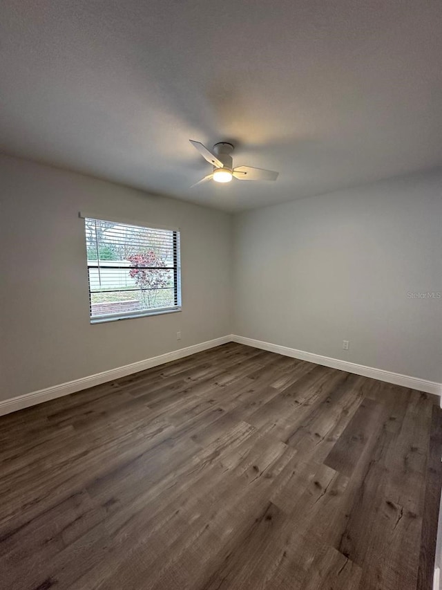 unfurnished room featuring dark wood-type flooring and ceiling fan