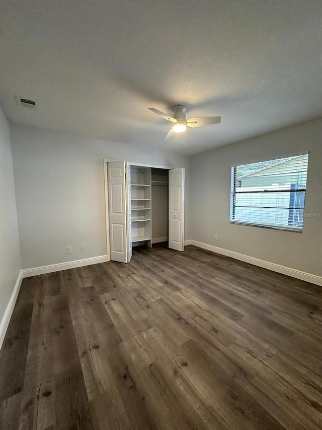 unfurnished bedroom featuring ceiling fan, dark hardwood / wood-style flooring, and a closet