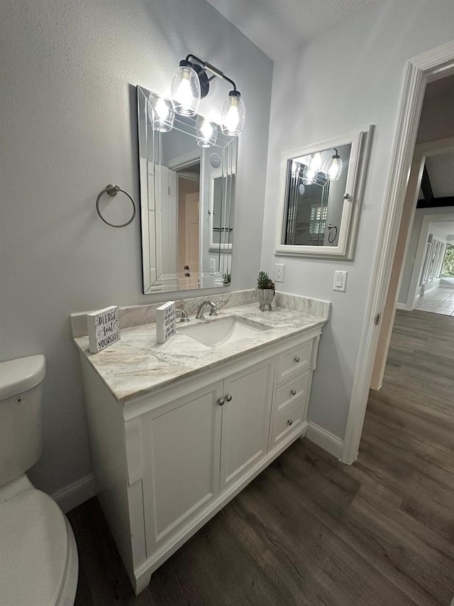 bathroom with toilet, vanity, and wood-type flooring