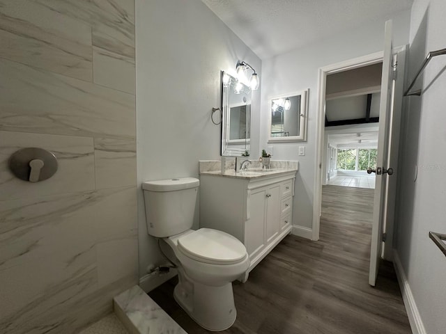 bathroom featuring wood-type flooring, toilet, vanity, and a textured ceiling