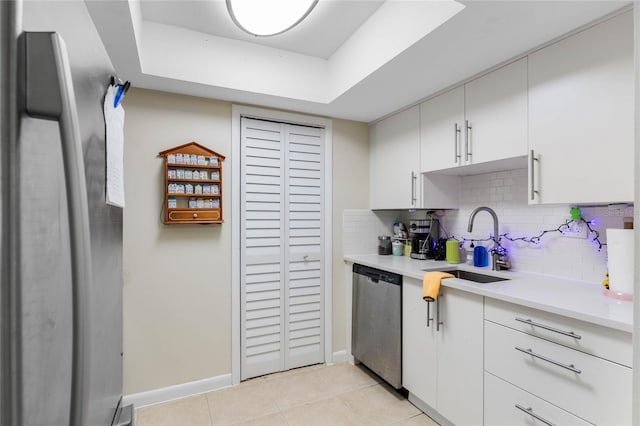 kitchen with white cabinets, dishwasher, tasteful backsplash, sink, and light tile patterned floors