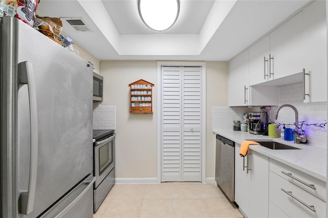 kitchen featuring backsplash, sink, white cabinetry, appliances with stainless steel finishes, and light tile patterned floors