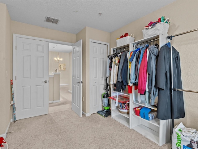 spacious closet with light colored carpet and a chandelier