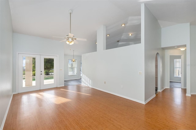 unfurnished living room with wood-type flooring, a wealth of natural light, high vaulted ceiling, and french doors