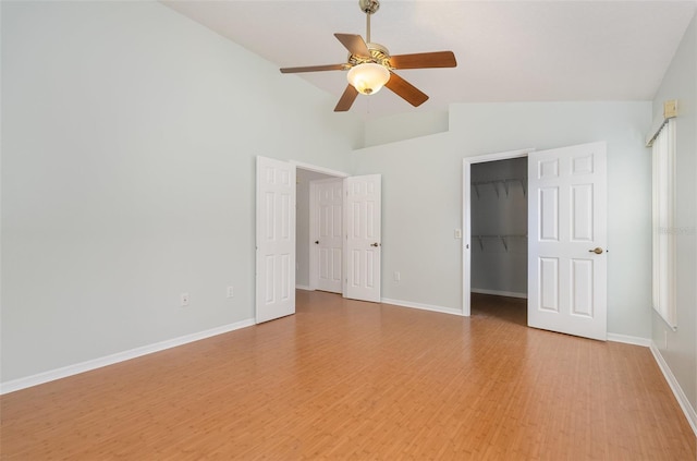 unfurnished bedroom with a walk in closet, light hardwood / wood-style floors, a closet, high vaulted ceiling, and ceiling fan