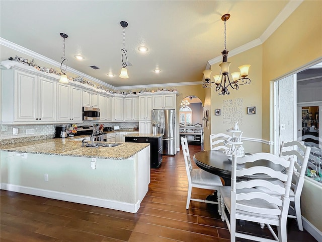 kitchen with decorative light fixtures, white cabinetry, stainless steel appliances, tasteful backsplash, and kitchen peninsula