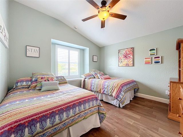 bedroom with ceiling fan, lofted ceiling, and light wood-type flooring