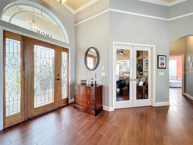 entryway featuring french doors, dark hardwood / wood-style flooring, a towering ceiling, and ornamental molding