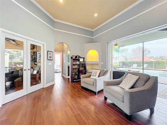 living room featuring a towering ceiling, dark hardwood / wood-style flooring, crown molding, and french doors