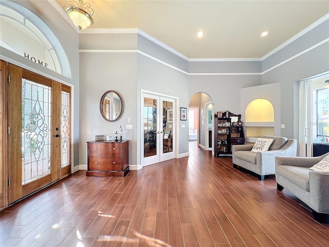 entryway featuring french doors, dark hardwood / wood-style floors, a towering ceiling, and ornamental molding