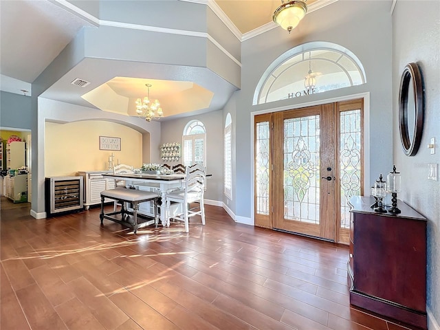 entryway with wine cooler, a raised ceiling, and a notable chandelier