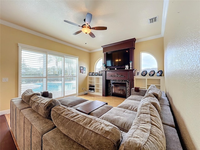 living room featuring a textured ceiling, ceiling fan, ornamental molding, and light wood-type flooring