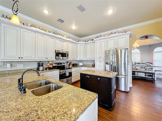 kitchen with a kitchen island with sink, appliances with stainless steel finishes, sink, and light stone counters