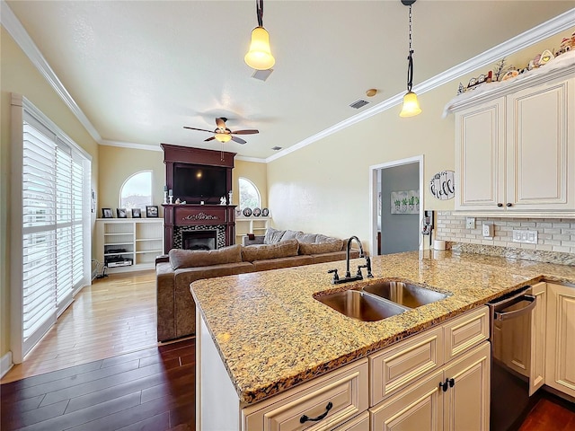 kitchen featuring light stone countertops, stainless steel dishwasher, hanging light fixtures, and sink