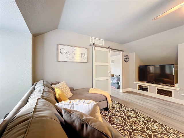 living room featuring lofted ceiling, a barn door, and wood-type flooring