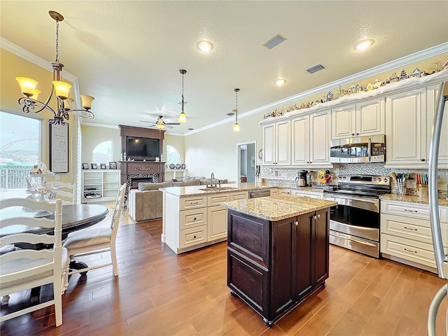 kitchen featuring light stone countertops, pendant lighting, stainless steel appliances, sink, and kitchen peninsula