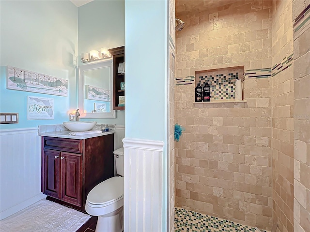 bathroom featuring toilet, vanity, and a tile shower