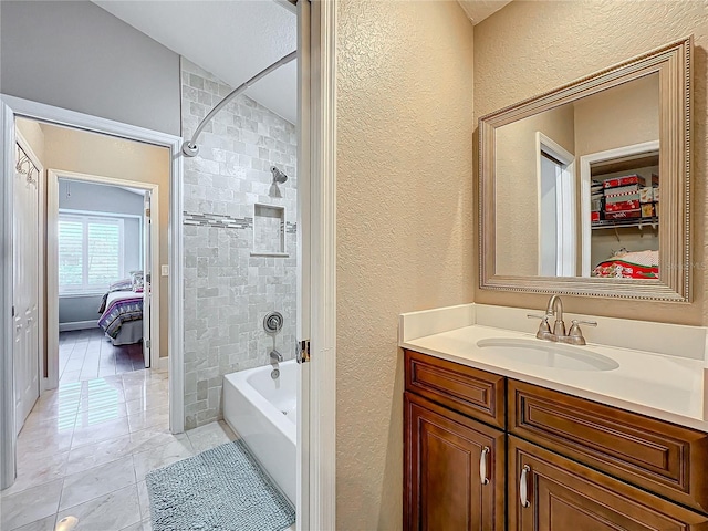 bathroom featuring tiled shower / bath and vanity