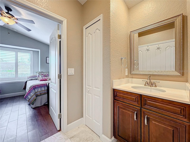 bathroom featuring ceiling fan, vanity, vaulted ceiling, and wood-type flooring