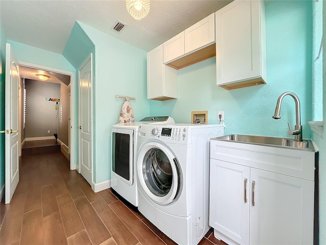 washroom featuring cabinets, sink, a textured ceiling, and washer and clothes dryer