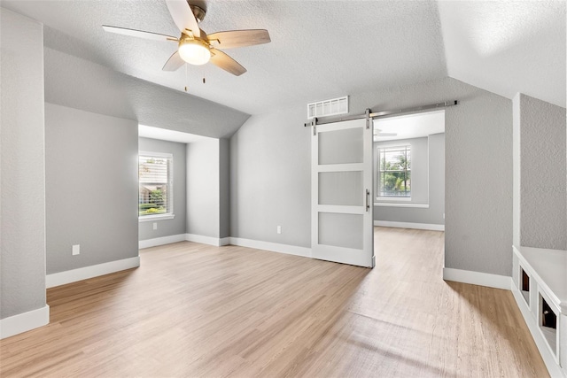 278 Eaglet Way, Lake Mary, FL 32746 - empty room featuring a barn door, plenty of natural light, light wood-style floors, a ceiling fan, and lofted ceiling