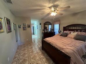 bedroom with ceiling fan and a textured ceiling