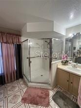 bathroom featuring a shower with shower door and vanity