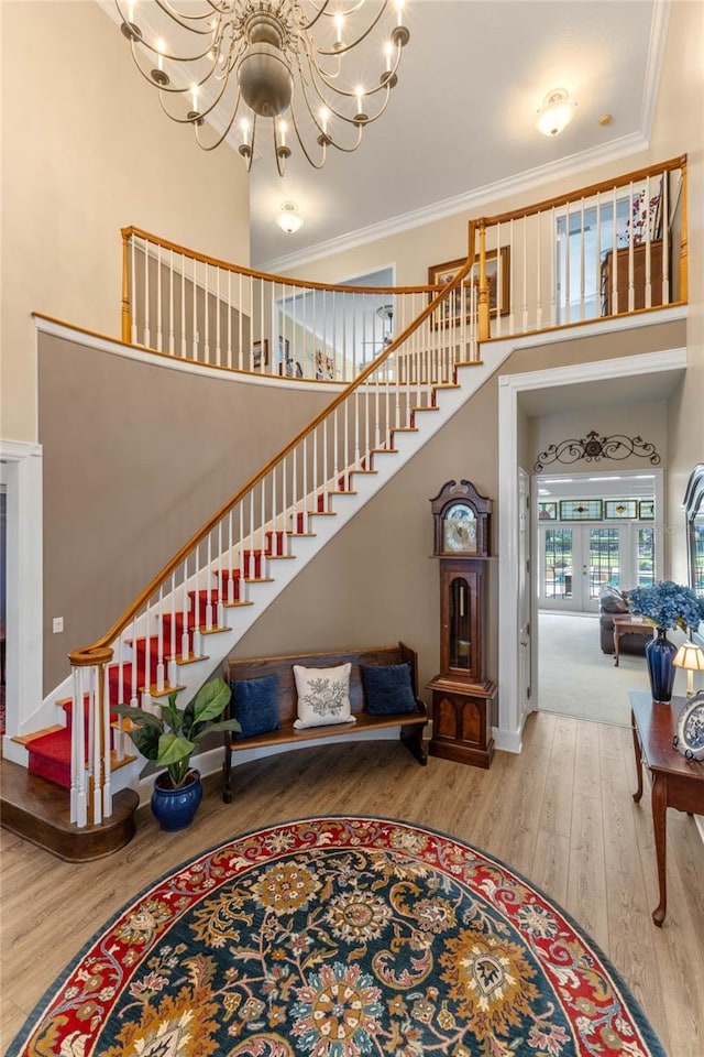 interior space featuring hardwood / wood-style flooring, ornamental molding, a towering ceiling, and a notable chandelier