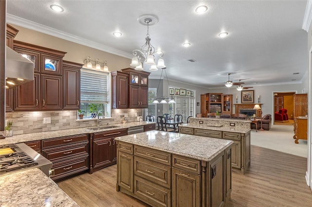 kitchen featuring crown molding, a kitchen island, sink, and pendant lighting