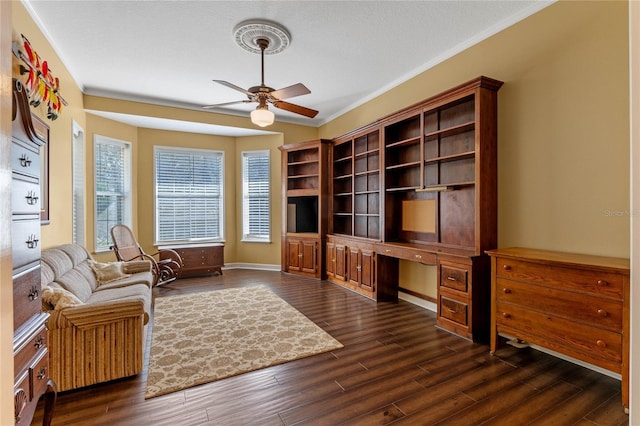 home office with dark wood-type flooring, ceiling fan, crown molding, and built in desk