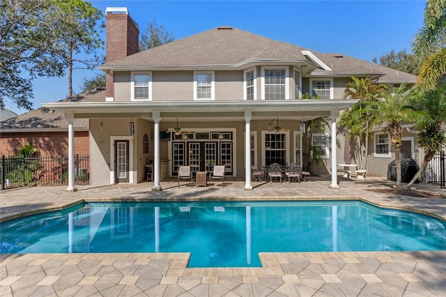 back of property featuring ceiling fan, a fenced in pool, and a patio area