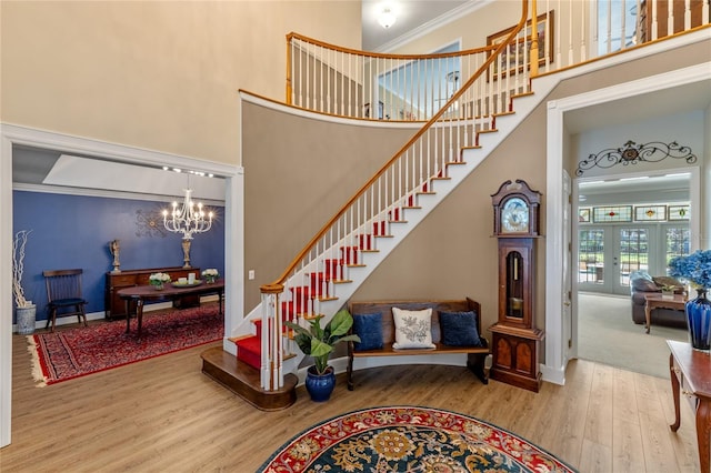 stairway featuring a chandelier, a high ceiling, wood finished floors, and baseboards