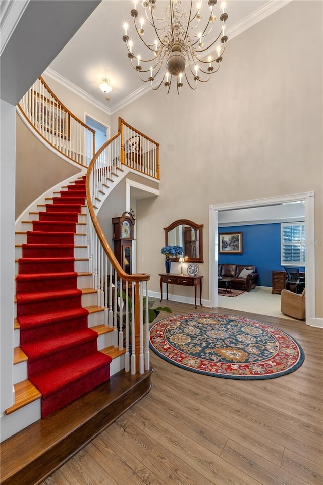 foyer entrance featuring ornamental molding, wood finished floors, a high ceiling, and baseboards