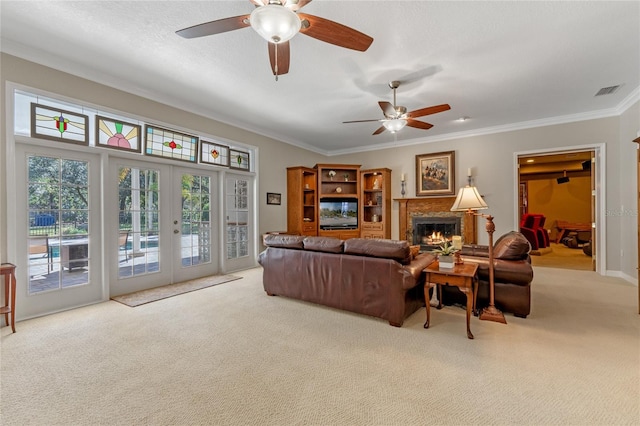 carpeted living area featuring visible vents, ornamental molding, a lit fireplace, a textured ceiling, and french doors