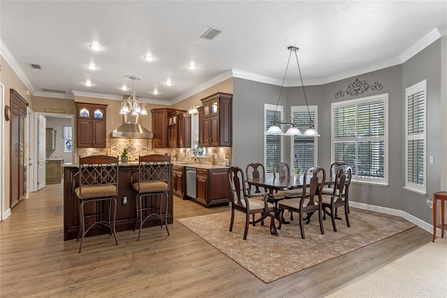 dining room featuring ornamental molding, visible vents, light wood-style flooring, and baseboards