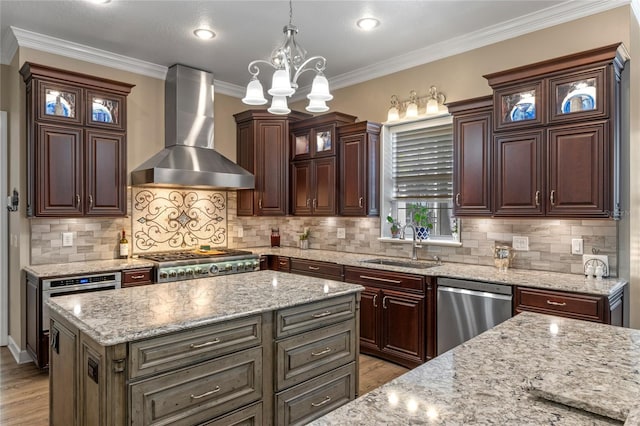 kitchen with light wood-style floors, glass insert cabinets, appliances with stainless steel finishes, wall chimney range hood, and a sink