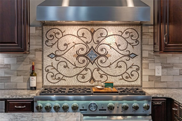 room details with wall chimney range hood, stove, backsplash, and dark brown cabinets