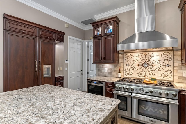 kitchen with wall chimney exhaust hood, range with two ovens, wine cooler, and backsplash