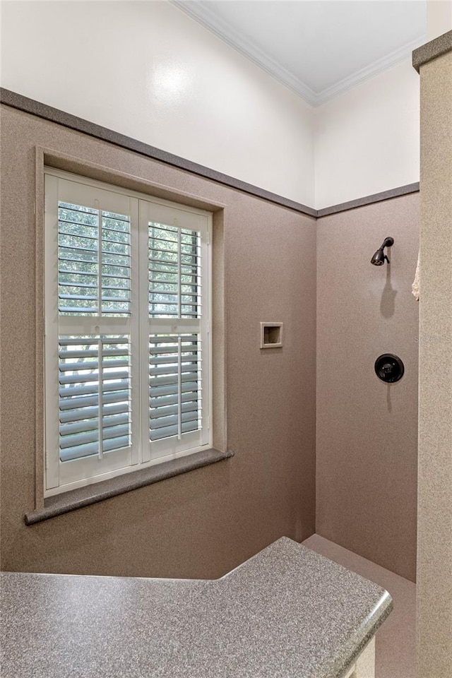 bathroom featuring tiled shower and crown molding