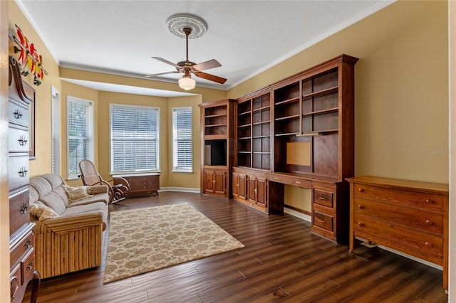 interior space with crown molding, dark wood finished floors, built in study area, ceiling fan, and baseboards