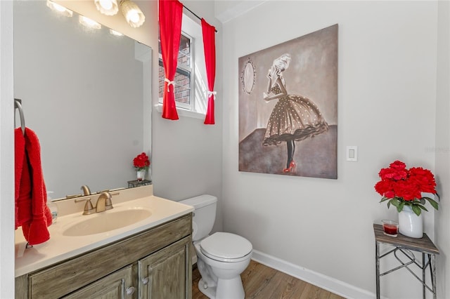 half bath with vanity, wood finished floors, toilet, and baseboards