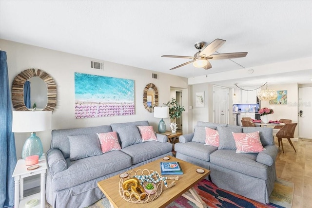 living room with ceiling fan with notable chandelier and parquet flooring