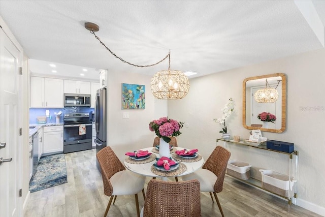 dining area featuring a textured ceiling, light hardwood / wood-style flooring, and a notable chandelier