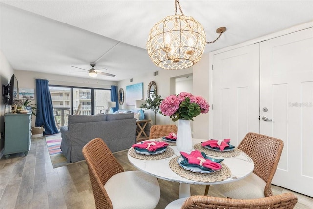 dining area featuring ceiling fan with notable chandelier and hardwood / wood-style floors