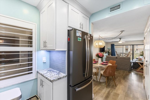 kitchen with white cabinets, light hardwood / wood-style floors, backsplash, stainless steel refrigerator, and ceiling fan