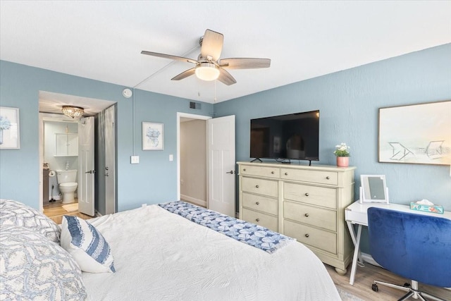 bedroom with light wood-type flooring, ceiling fan, and ensuite bath