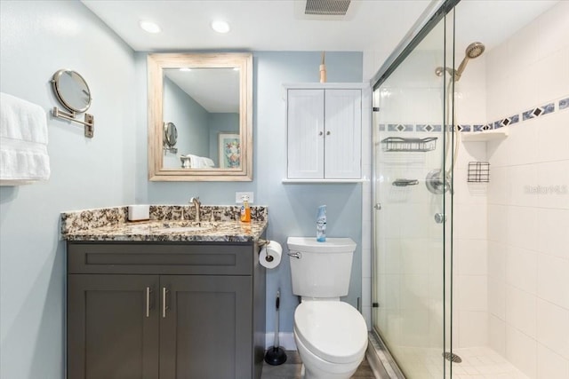 bathroom with toilet, an enclosed shower, and vanity