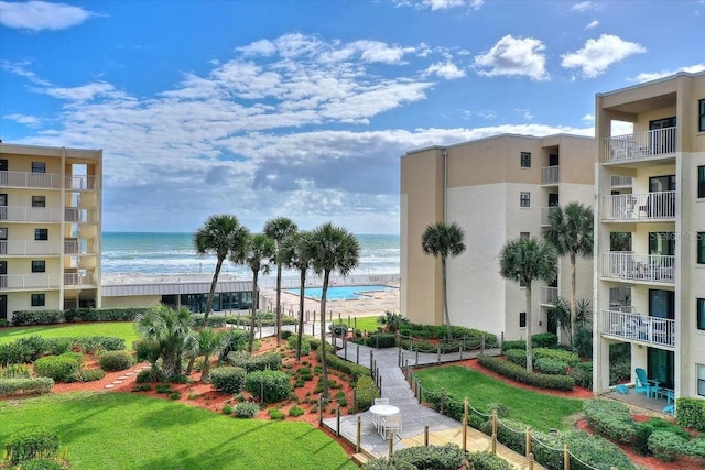 view of home's community featuring a beach view, a yard, and a water view