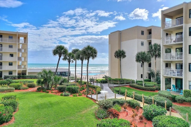 surrounding community featuring a lawn, a water view, and a beach view