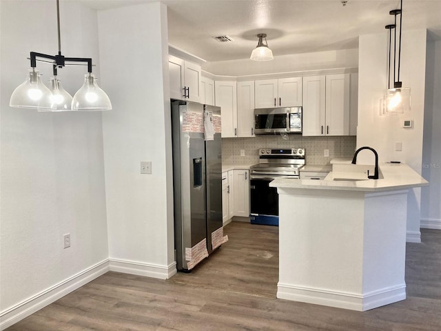 kitchen with sink, hanging light fixtures, white cabinets, and stainless steel appliances